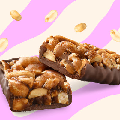 Box of N!CK'S Peanut Crunch Nut Bars (12-pack), with bars unwrapped to show the crunchy peanut filling coated in chocolate. Highlights "no added sugar" and "100% pleasure."